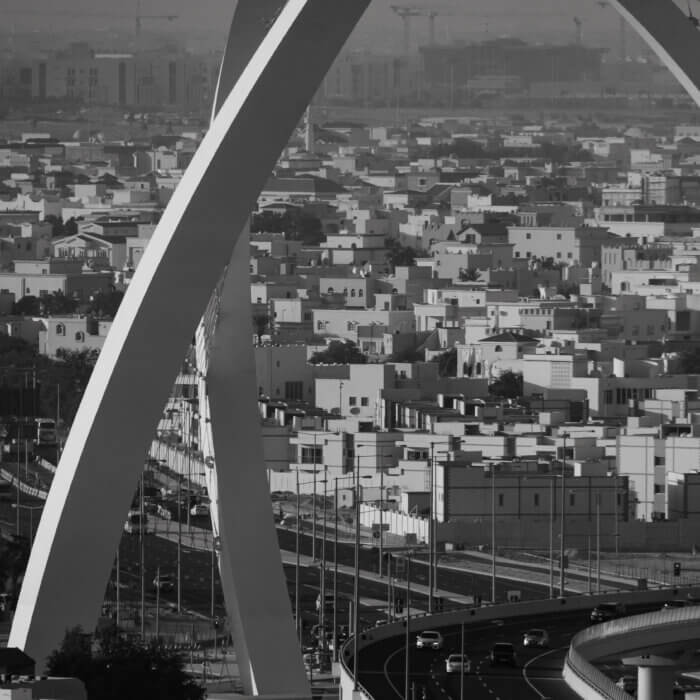 Image shows arch structure in Doha, Qatar with residential homes in background
