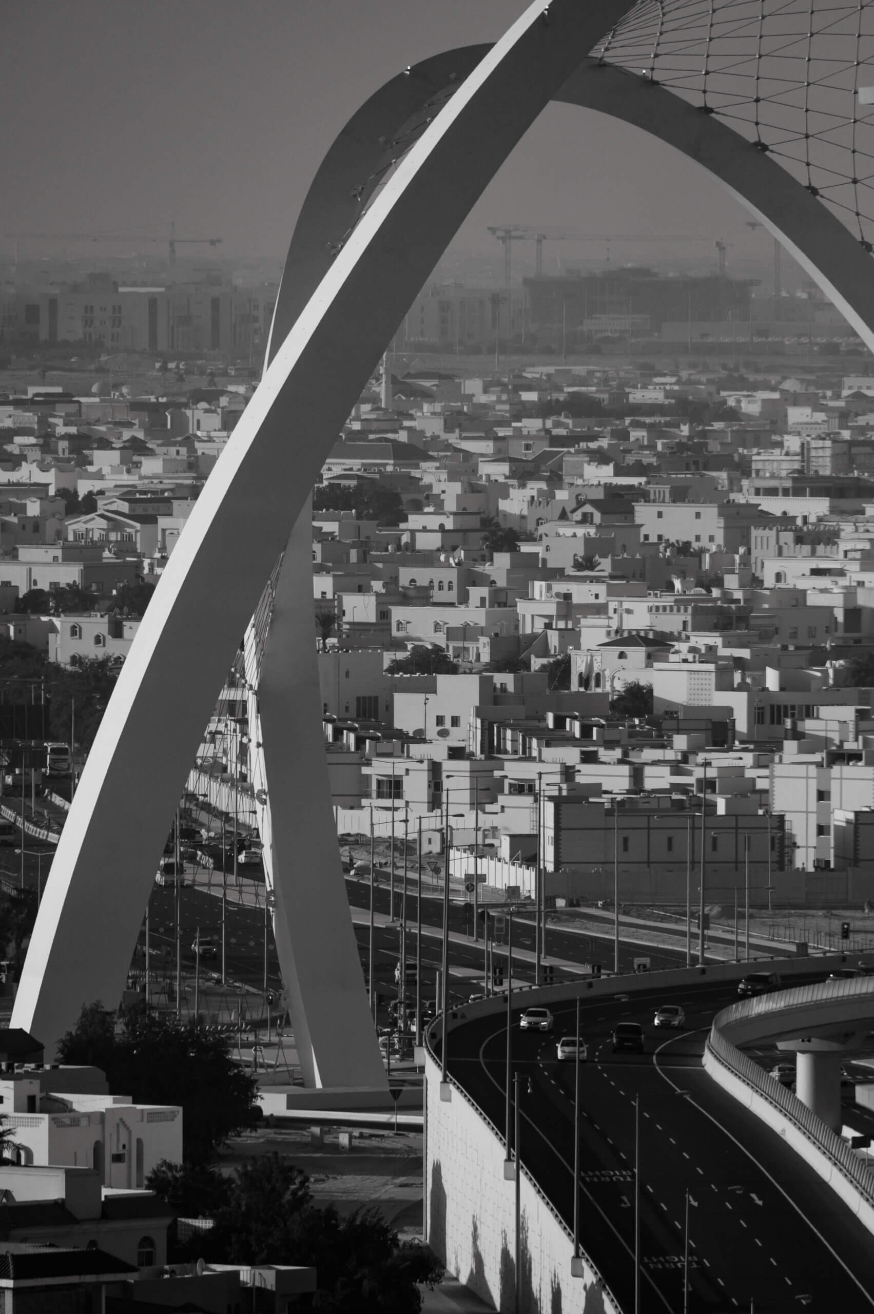 Image shows arch structure in Doha, Qatar with residential homes in background